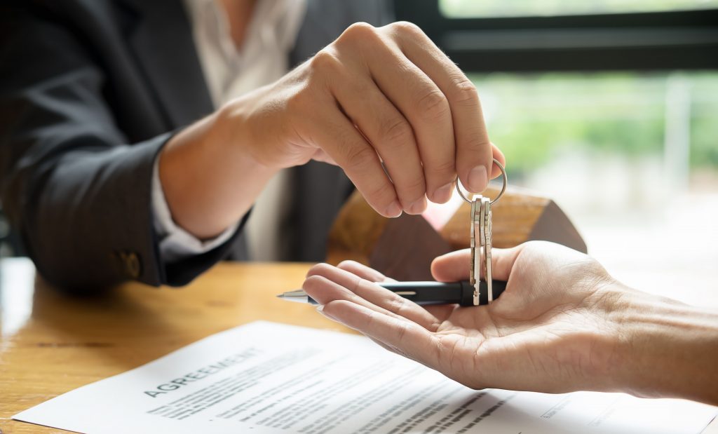 real estate agent handling keys to agent